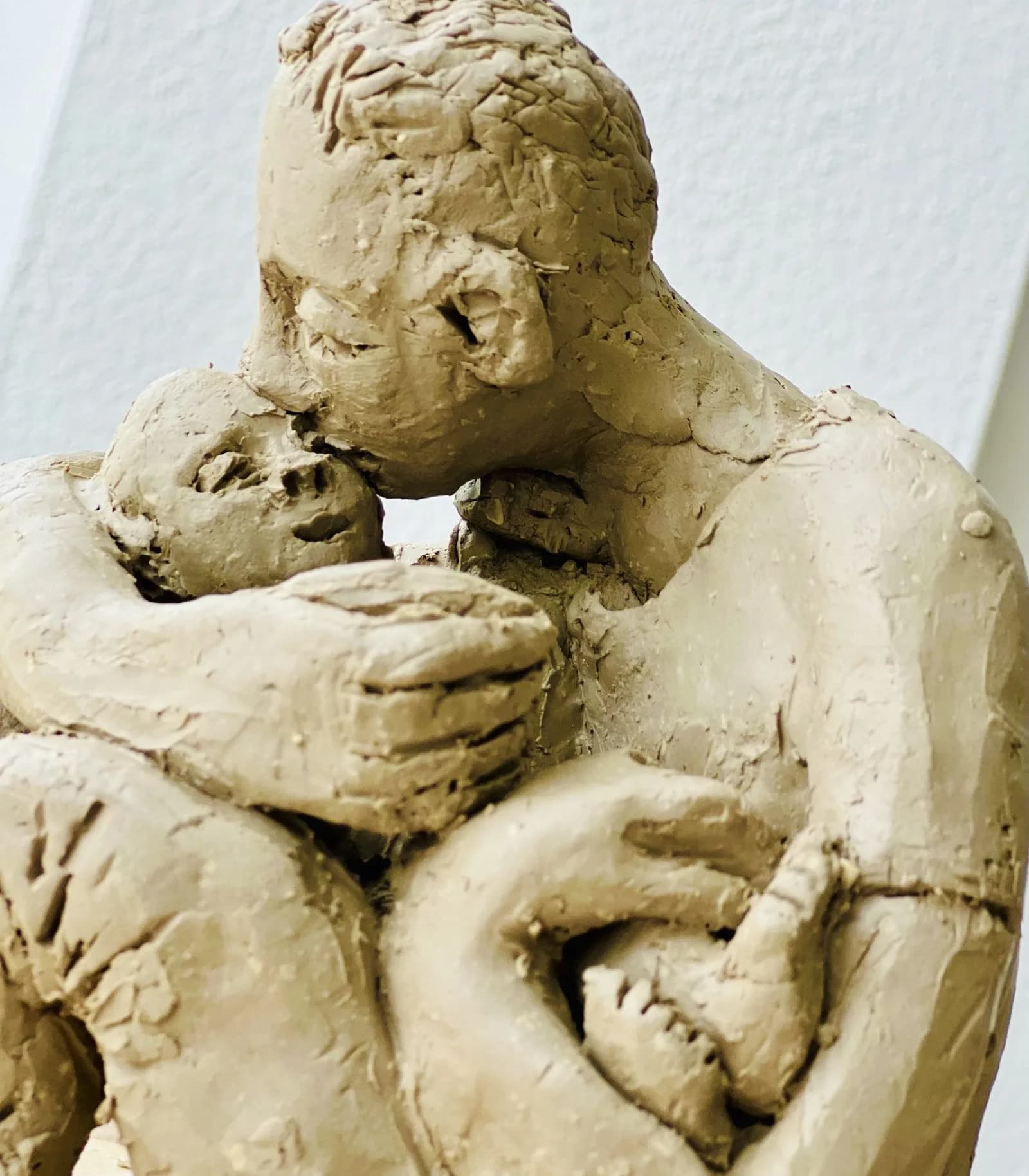 Ungebrannte Tonskulptur eines eng umarmten Paares.