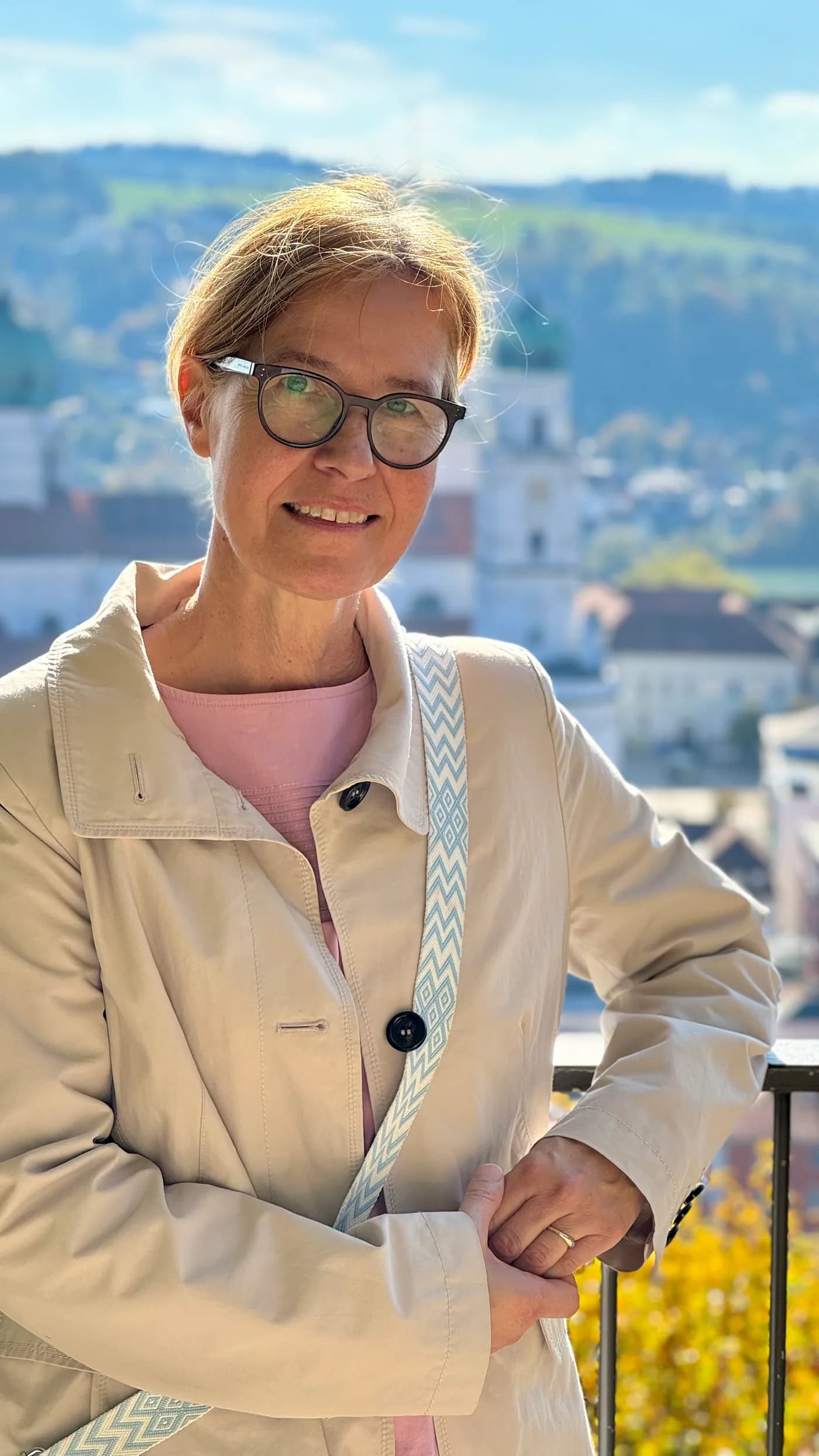 Beatrix „Trixi“ Diedenhofen lächelt in die Kamera, im Hintergrund eine Voralpenlandschaft mit Kirchturm